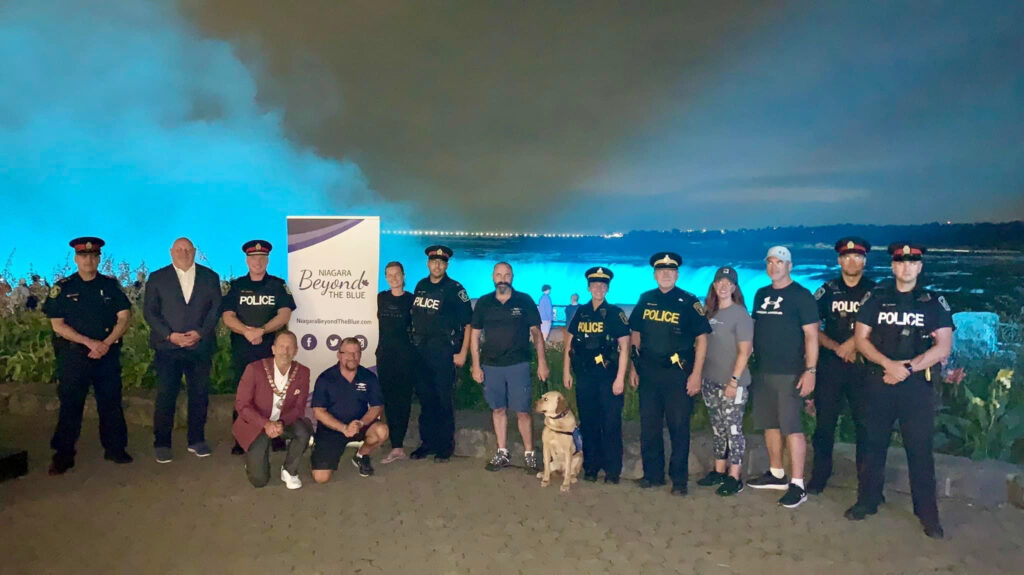 Niagara Beyond The Blue in front of Niagara Falls. Niagara BTB had the falls lit teal in honour of National PTSD Awareness Day.